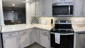 A kitchen with white cabinets, a black stove, and a microwave. - B2 Boujee, a ground floor, cozy condo, just a short walk to the beach.. (Gulf Shores)