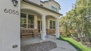 A residential house with the number 6055, a stone bench, and a landscaped front yard. - Space Command (Colorado Springs)