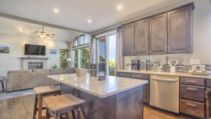 A modern kitchen with dark wood cabinets, a large island, and a built-in oven. - Space Command (Colorado Springs)