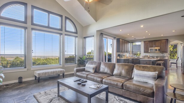 A spacious living room with a leather sofa, a coffee table, and large windows. - Space Command (Colorado Springs)
