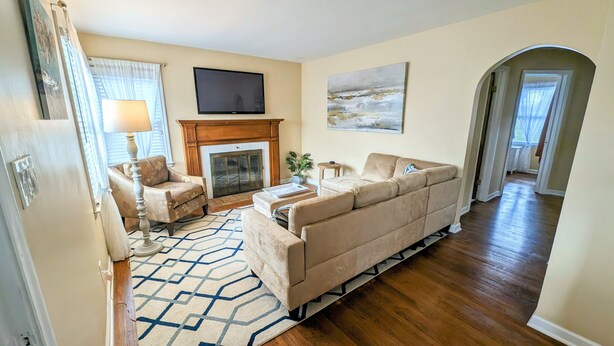 A living room with a sofa, armchairs, a fireplace, a television, and a patterned rug. - Cozy family retreat (Buffalo)