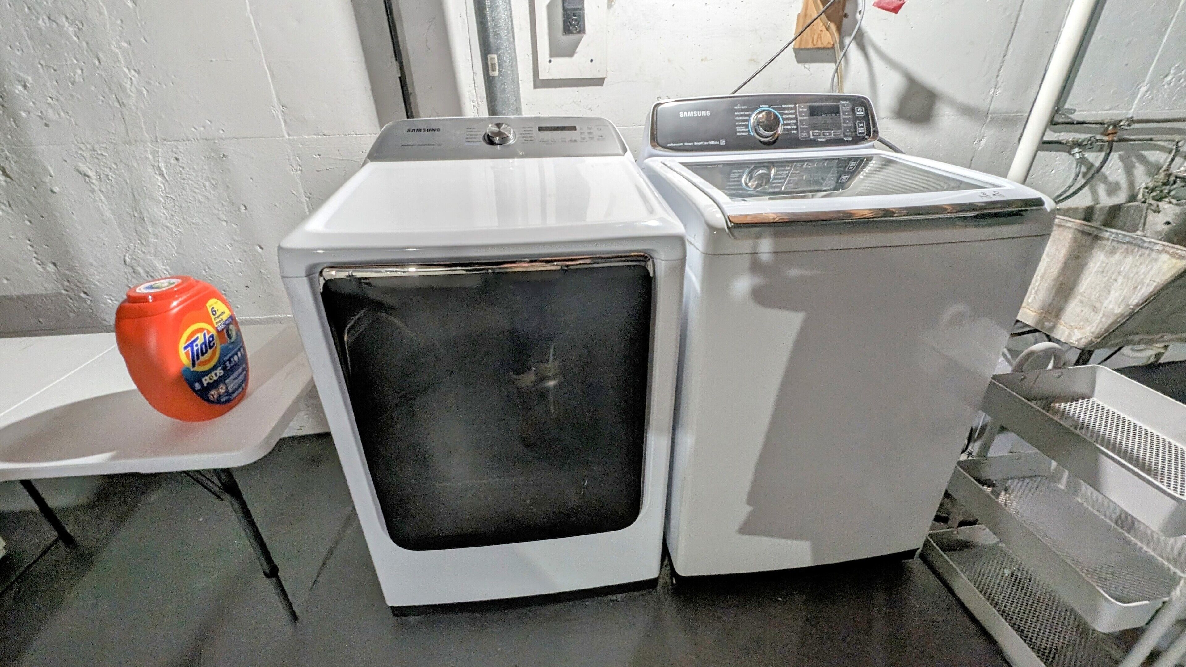 A front-loading washing machine with a control panel, a detergent bottle, and a metal rack.