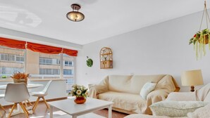 A modern living room with a sofa, a coffee table, and a dining area with chairs.
