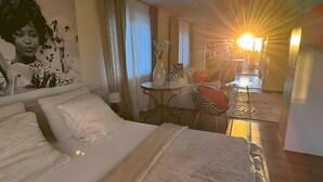 Una habitación de hotel con cama, escritorio, silla y zona de comedor.