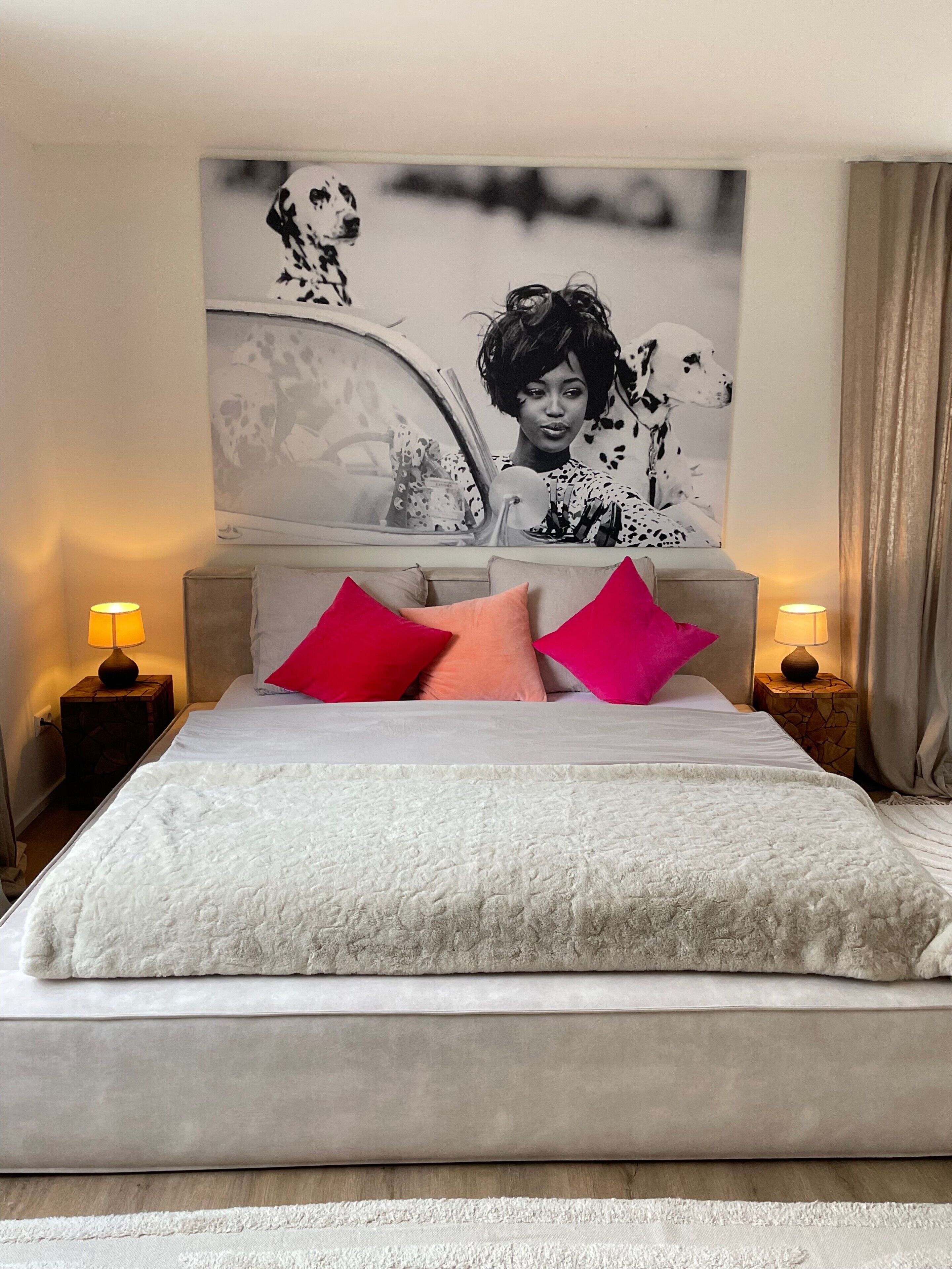 A bedroom with a bed, pillows, a headboard, and a wall art piece.