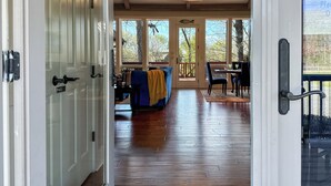 A spacious living area with a large window, a blue sofa, and a dining table. - Riverfront Bliss- Private River Dock & Two King rooms! (Pangburn)