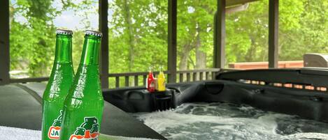 Two bottles of JARITOS grapefruit soda on a towel, with a hot tub and outdoor view in the background.