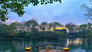 A wooden dock leading to a boat, surrounded by trees and a building with lights in the background. - Riverfront Bliss- Private River Dock & Two King rooms! (Pangburn)