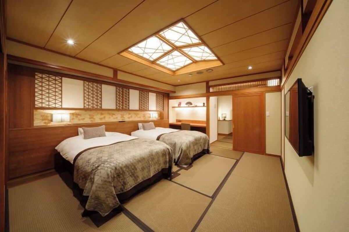 A traditional Japanese-style room with tatami flooring, a skylight, and a sliding door leading to a bathroom.