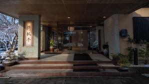 Une entrée moderne, avec un plafond en bois, une enseigne avec des caractères chinois et des plantes en pot.