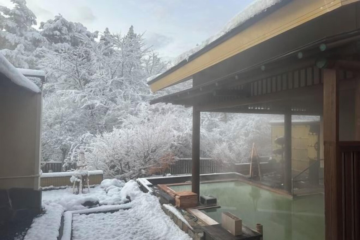 A snow-covered outdoor area with a hot tub and wooden deck.