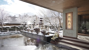 Un jardin japonais traditionnel avec un sentier de pierres menant à une entrée en bois.