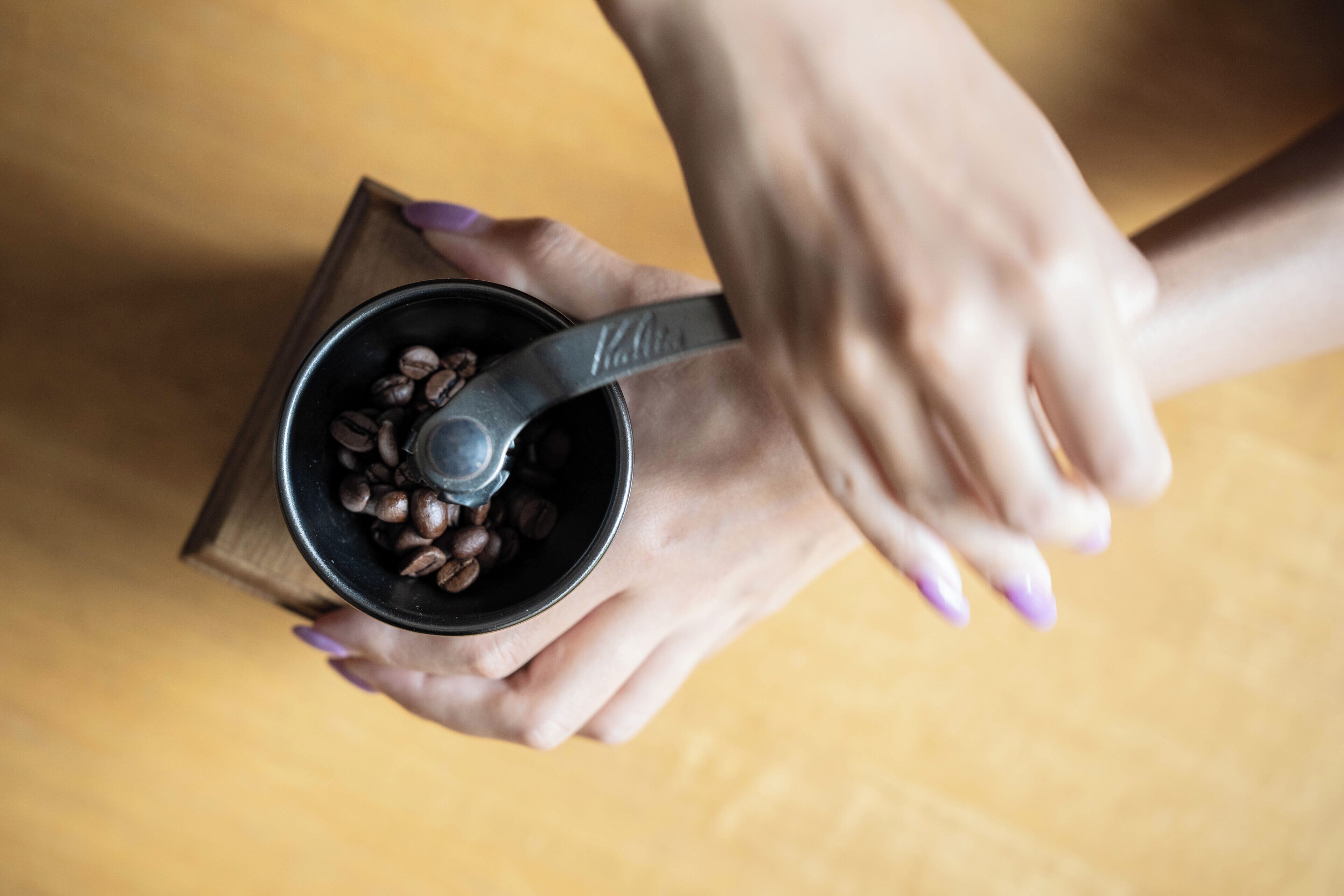 Une personne tenant une tasse remplie de grains de café et une cuillère.