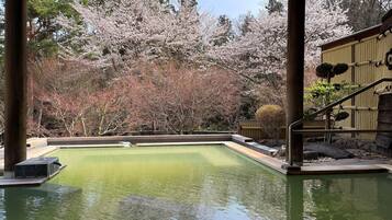 Piscina con vistas a flores de cerezo y una estructura de bambú.