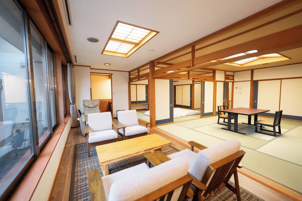 A traditional Japanese room with tatami flooring, a low table, and chairs.