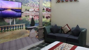Una sala de estar con un televisor grande, un sofá, una mesita y una pared decorativa con un cuadro.