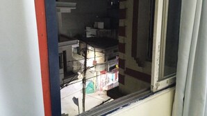 Vista a través de una ventana que muestra un edificio de varios pisos y un balcón.