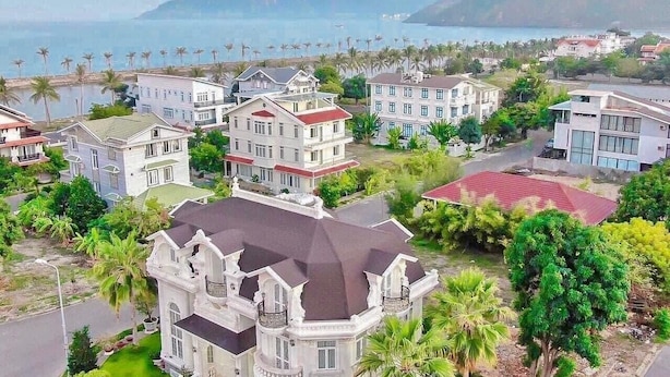 Un quartier résidentiel situé sur la côte, composé de nombreuses maisons à deux étages, dotées de balcons et offrant une vue sur la mer.
