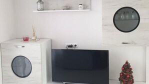 Ein modernes Wohnzimmer mit einem Flachbildfernseher, einer Waschmaschine und einer kleinen Weihnachtstanne.