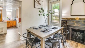 A dining area with a wooden table, black chairs, and a vase with branches. There is a fireplace with a decorative mantle and a framed picture on the wall. - ☆New! Central+FreeParkin+GYM+Kingbed (Pittsburgh)