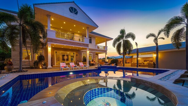 Una casa grande de dos pisos con piscina y jacuzzi.