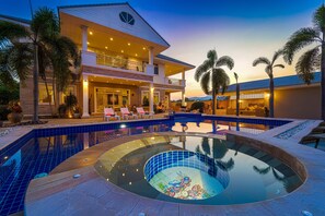 Une grande maison à deux étages, dotée d’une piscine et d’un jacuzzi.