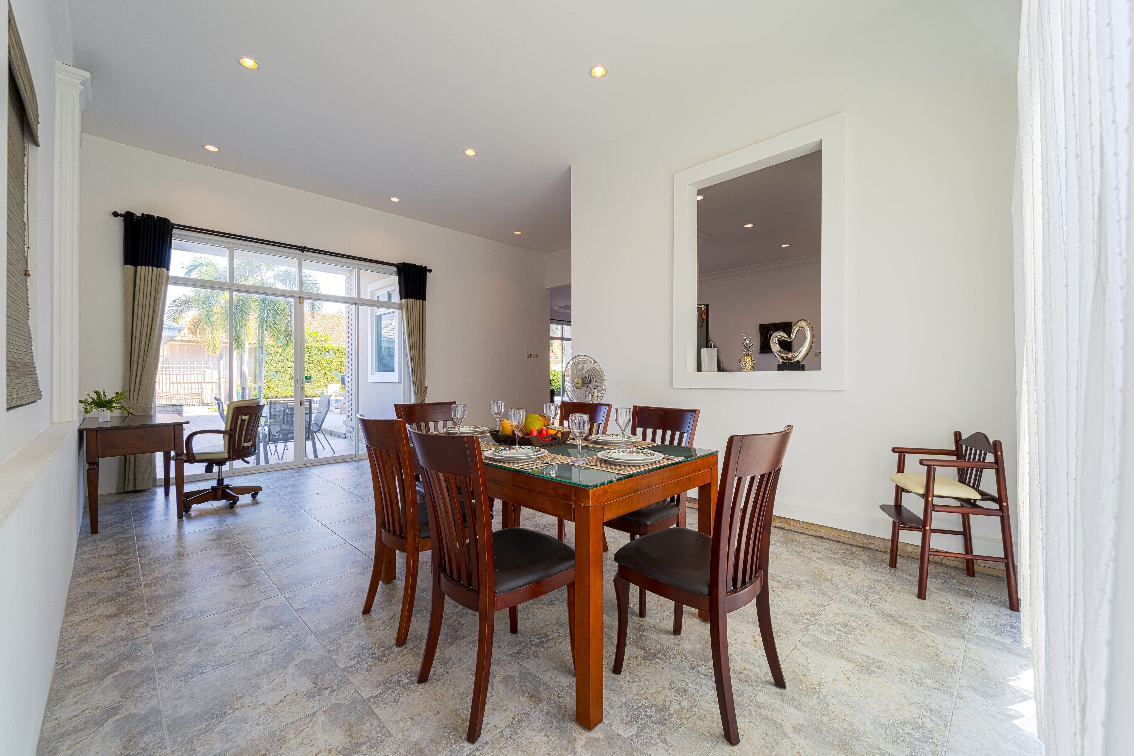 Un espace repas avec une table à plateau en verre, des chaises en bois et une vue sur l’extérieur.