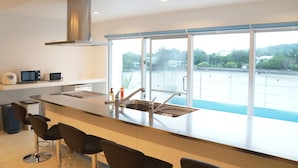 Una cocina moderna con un amplio ventanal, una campana extractora de acero inoxidable y una zona de bar con taburetes.