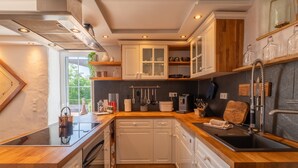 A modern kitchen with wooden countertops, white cabinetry, and a black sink. - Charming Eifel Bakehouse with Sauna, Private Terrace & EV Charging (Feuerscheid)