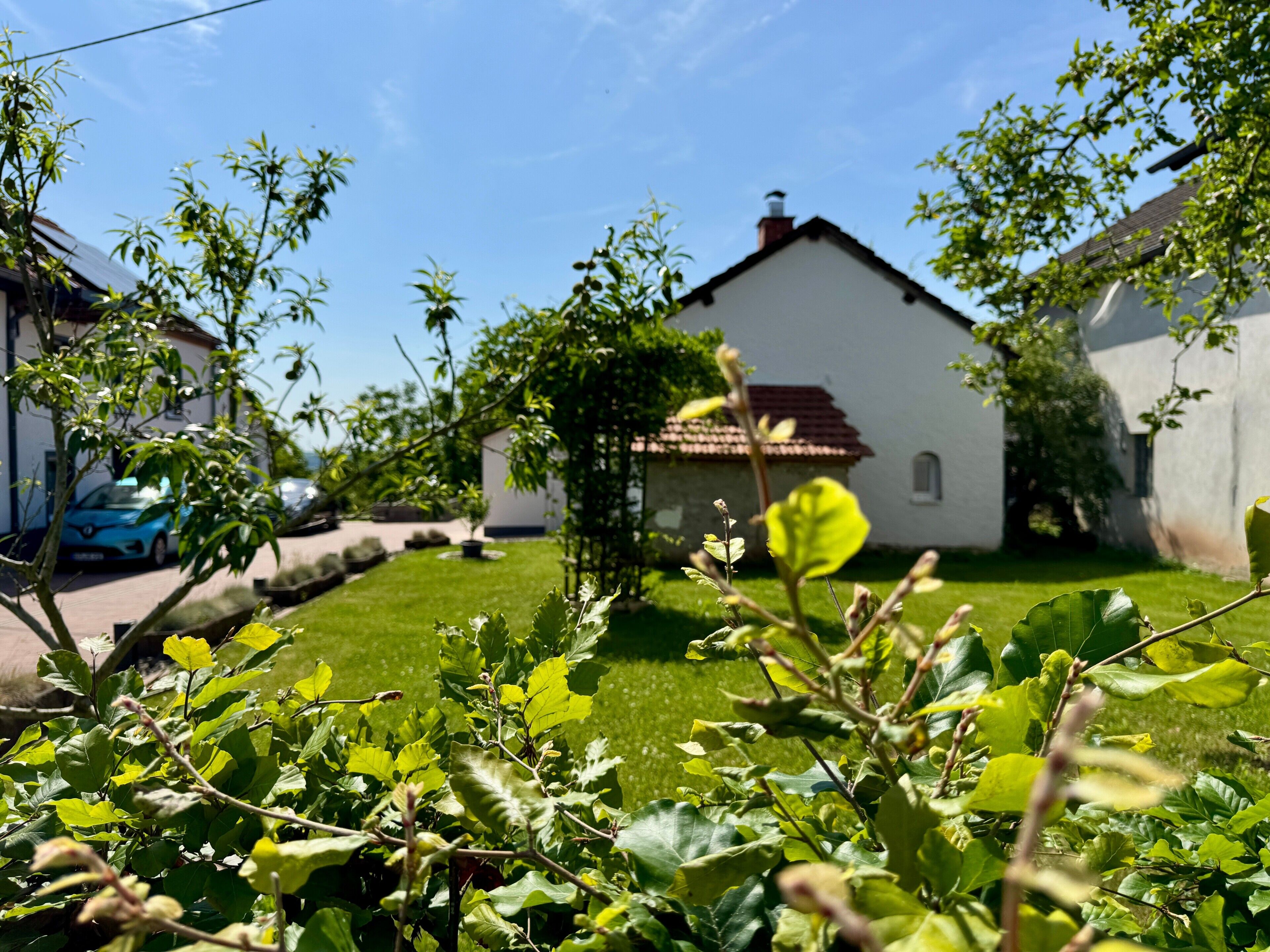 A residential house with a red-tiled roof, a small garden, and a parked car.