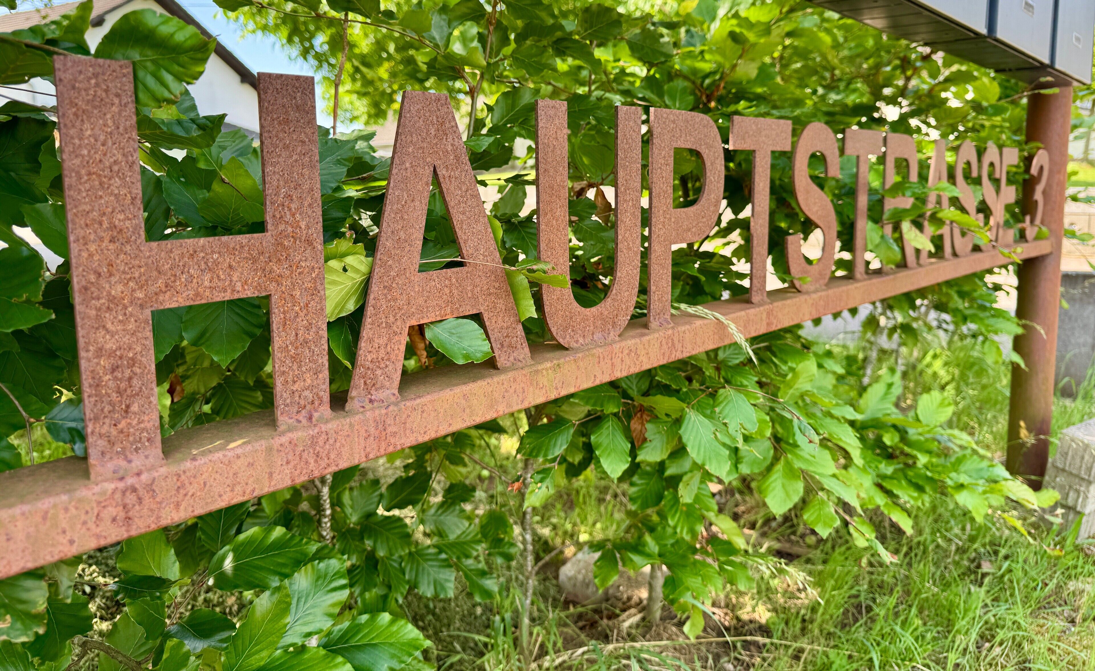 A metal sign with the text 'HAUPTSTADT' amidst greenery.
