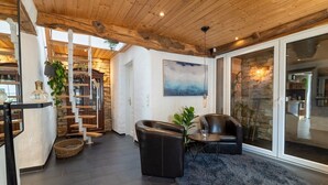 A modern interior with a staircase, seating area, and a large window. - Charming Eifel Bakehouse with Sauna, Private Terrace & EV Charging (Feuerscheid)