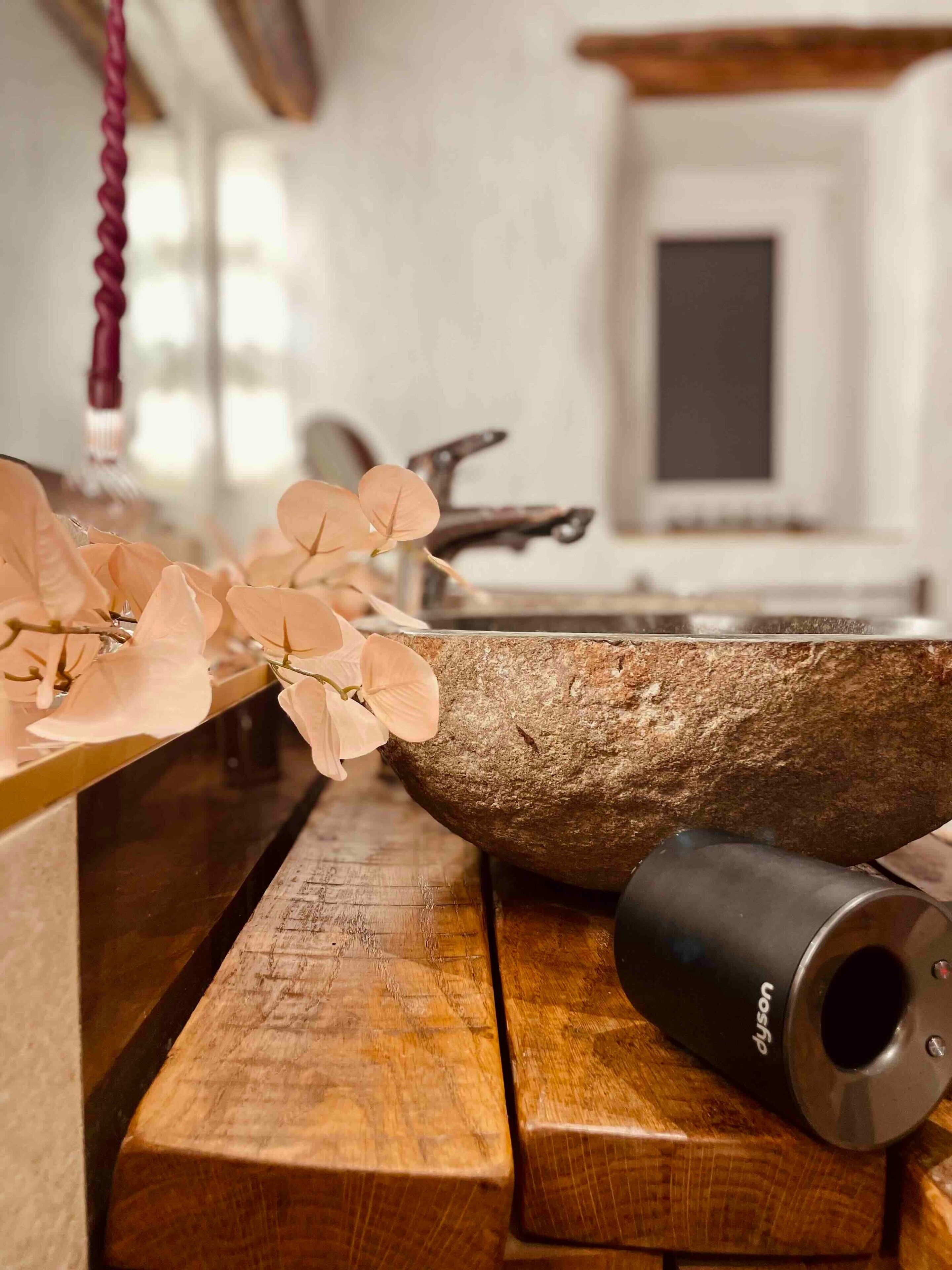 Un banco de madera con un cuenco de piedra y un aspirador Dyson.