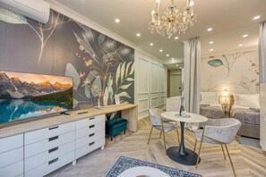 Uma sala moderna com televisão, área de refeições e quarto.