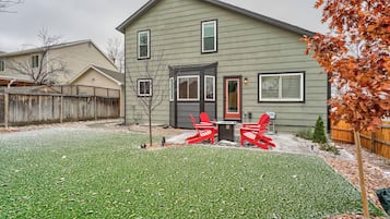 A two-story house with a front yard, a wooden fence, and a small tree.