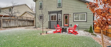A two-story house with a front yard, a wooden fence, and a small tree.