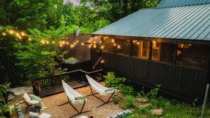 A wooden cabin with a deck, outdoor seating, and string lights. - New Hot Tub, Hammocks, Pet Friendly, Romantic Honeymoon Mountain Getaway (Pigeon Forge)