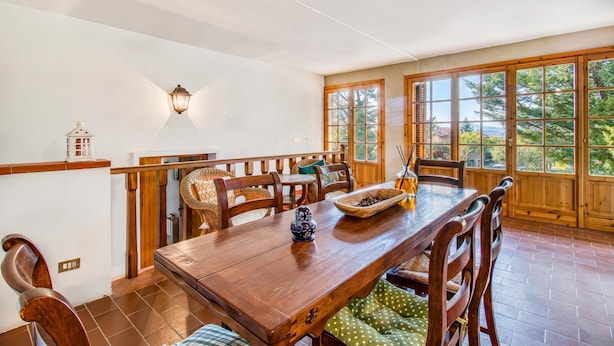 Un espace repas avec une table en bois, des chaises et une vue dégagée grâce à de grandes fenêtres.