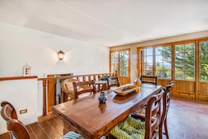 A dining area with a wooden table, chairs, and a view through large windows. - Casa Acone In Mugello - Near Florence (Pontassieve)