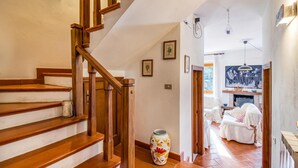 Un escalier avec des rampes en bois, un sol carrelé et un vase posé sur la plateforme.