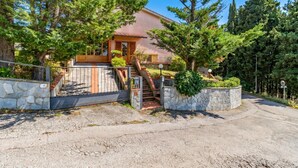 Une maison avec un portail en pierre, un escalier en bois et une allée pavée.