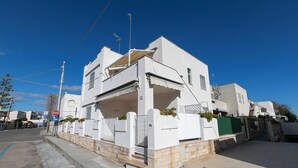 A two-story white building with a balcony, a gated entrance, and a clear blue sky. - Bel Mare Apartment 200m from beach  (Melendugno)