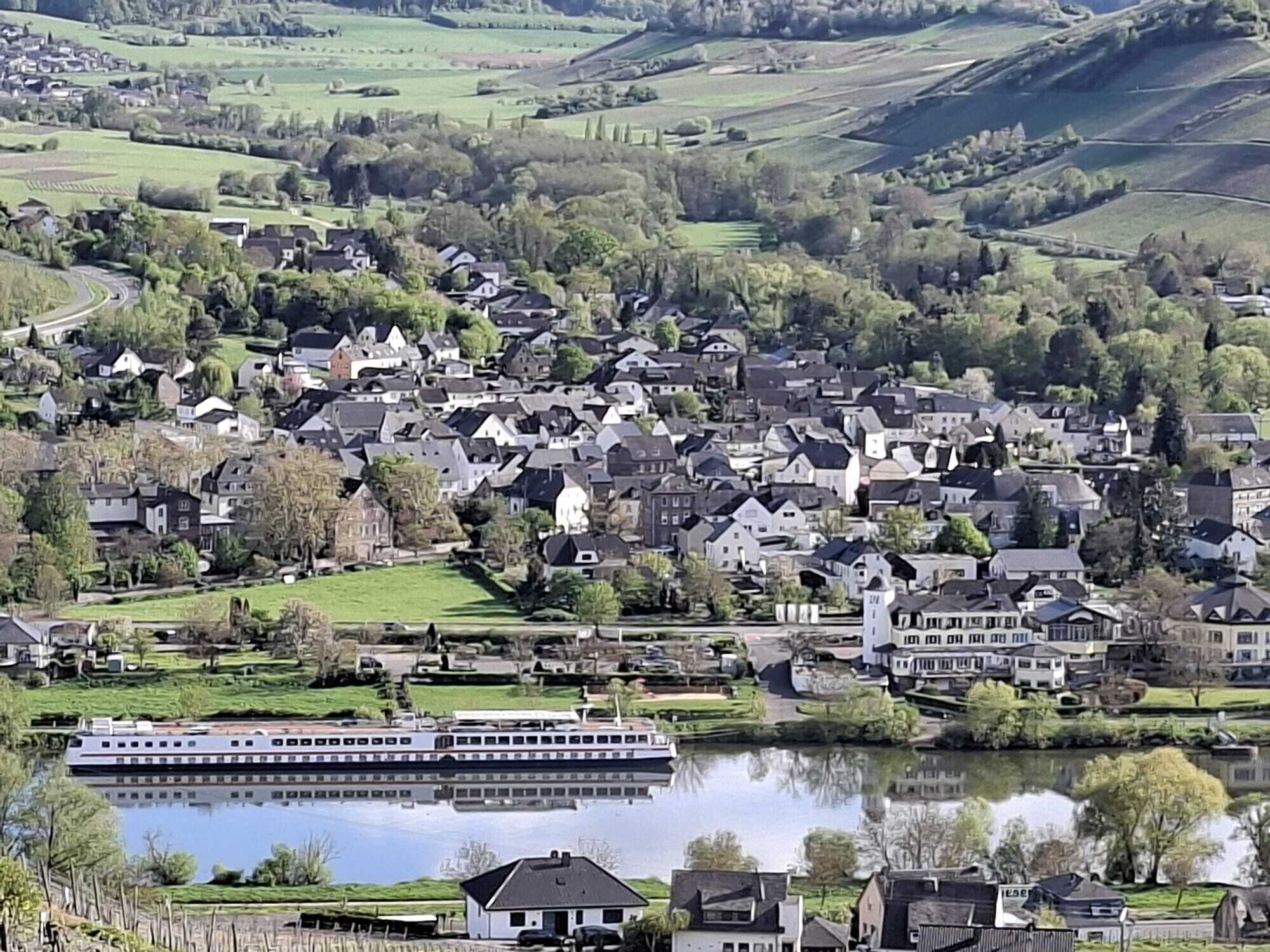 Une ville riveraine où se côtoient des maisons d’habitation et un grand bateau amarré près de l’eau.