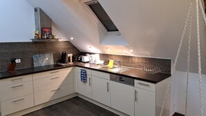 A modern kitchen with a skylight, built-in appliances, and a dark countertop. - Urgemütliche Ferienwohnung, Offenes Spitzdach Nähe Weinanbaugebieten (Salmtal)