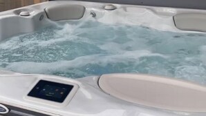Un bain à remous doté d’un panneau de commande et d’une base en bois.