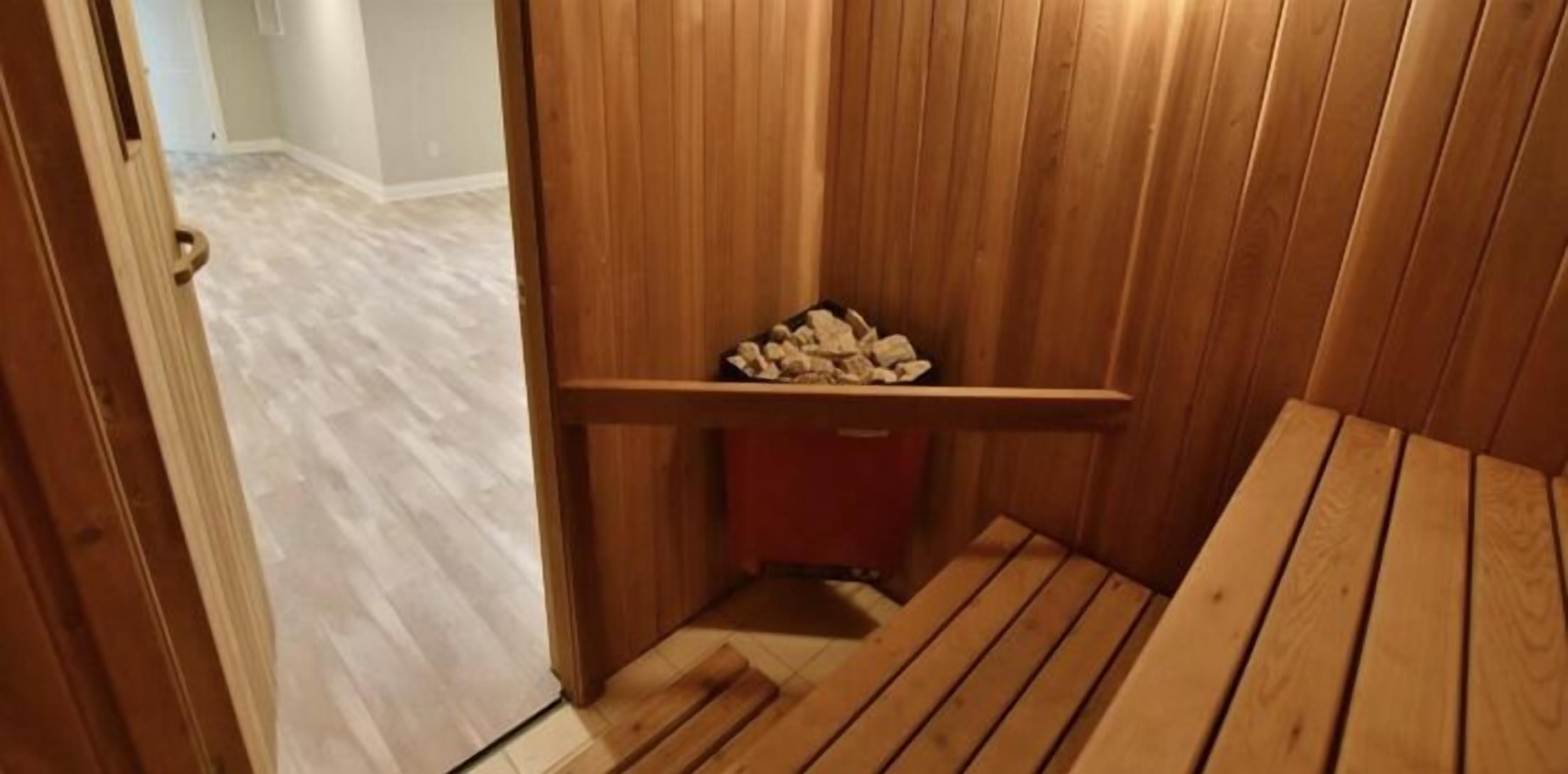 Un banco de madera con un pequeño estante que sostiene leña, una puerta de madera y un suelo de color claro.