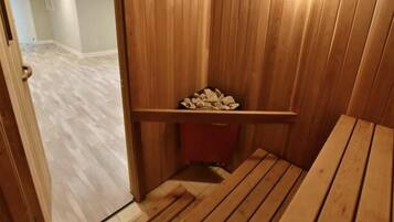 Un banco de madera con un pequeño estante que sostiene leña, una puerta de madera y un suelo de color claro.