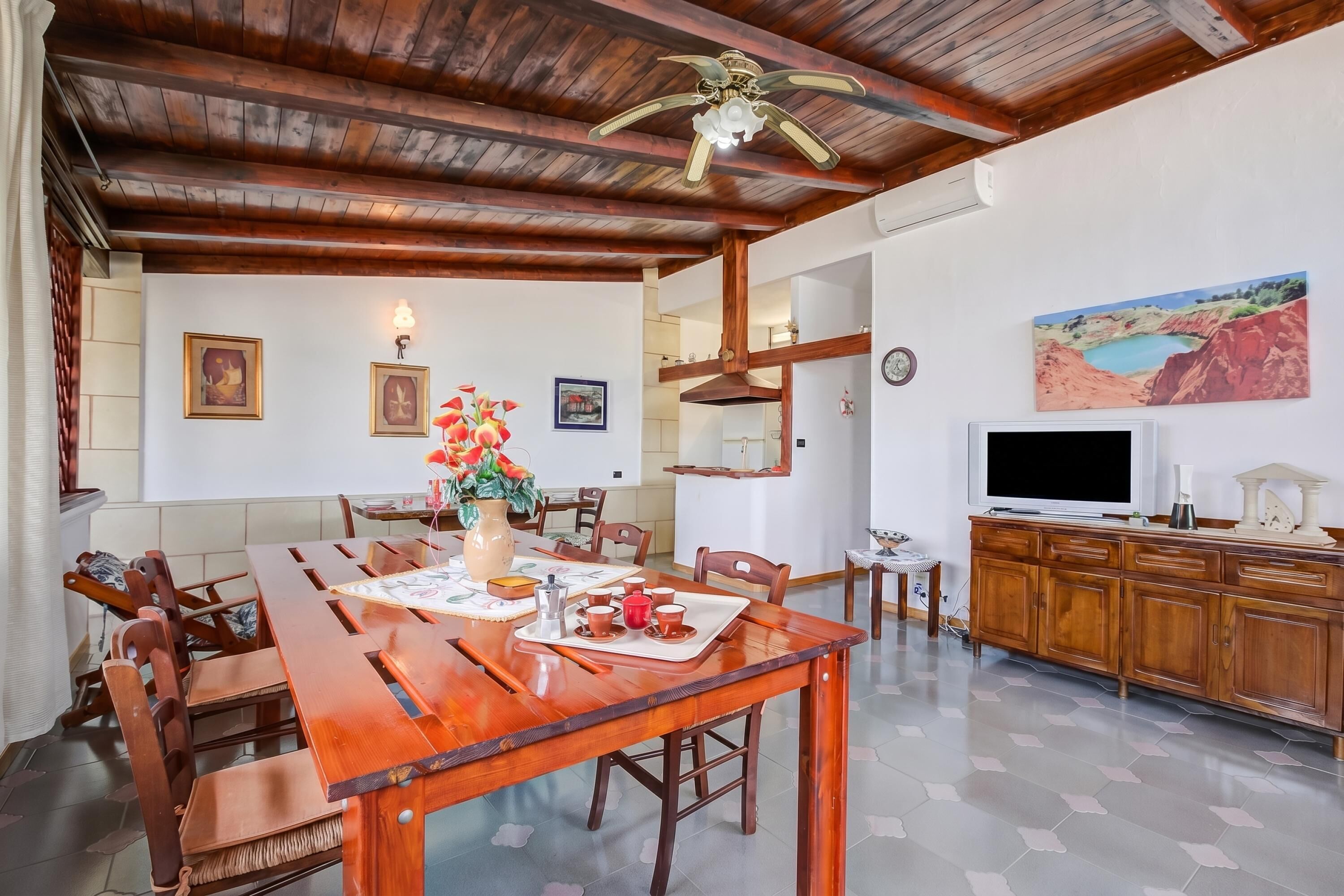 A dining area with a wooden table, chairs, and a ceiling fan.