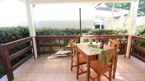 A balcony with a wooden table and chairs, a bottle of wine, and a green placemat. - Bungalow Fragola with Shared Pool, Wi-Fi, and Air Conditioning in Otranto (Otranto)