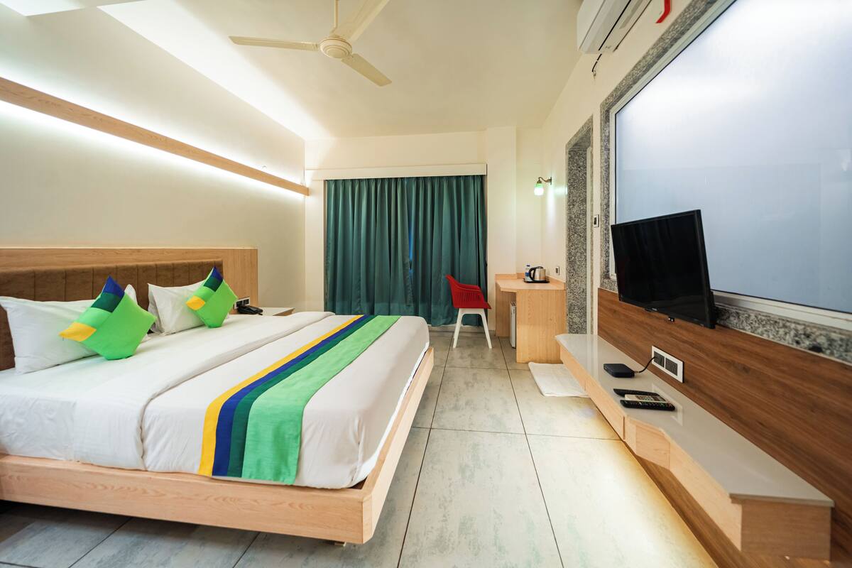 A hotel room with a bed, a desk, a television, and a ceiling fan.